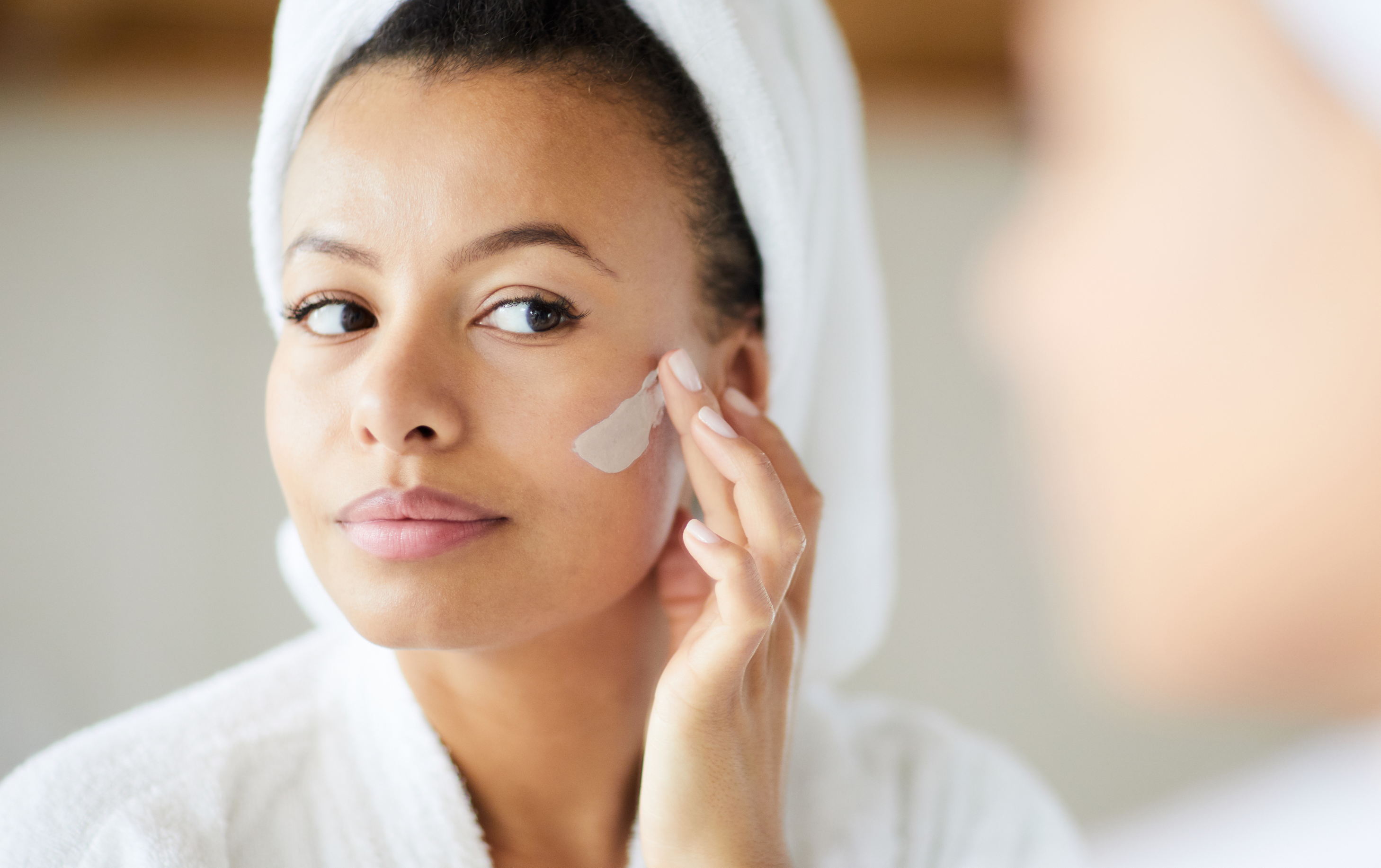 woman applies CBD skincare to her face for CBD skincare benefits