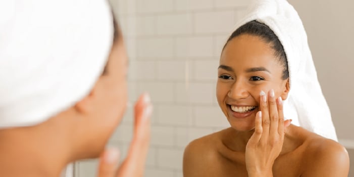 A happy woman with positive self-esteem puts on skin care