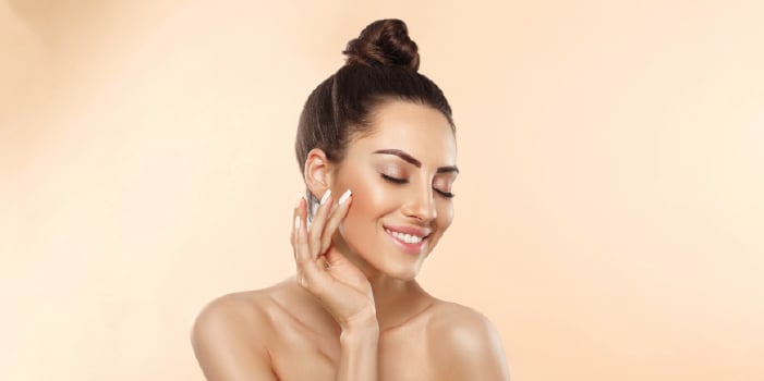 A woman with positive self-esteem feeling her soft, glowing skin.
