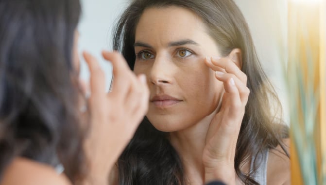 Woman examining her skin to see how hormones are affecting her skin health.