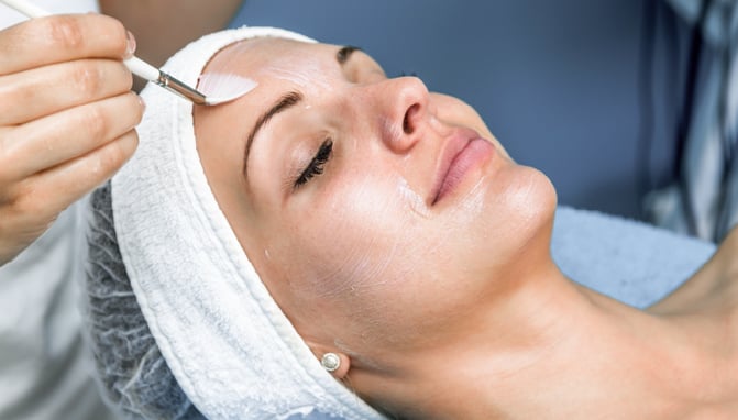 Woman receives a chemical peel treatment from an esthetician
