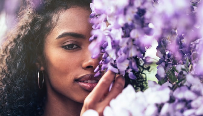 Woman who does spring skin care stands next to flowers