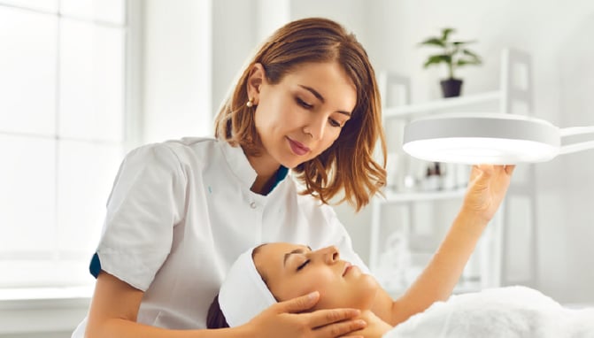 Aesthetician performing a facial on a client.