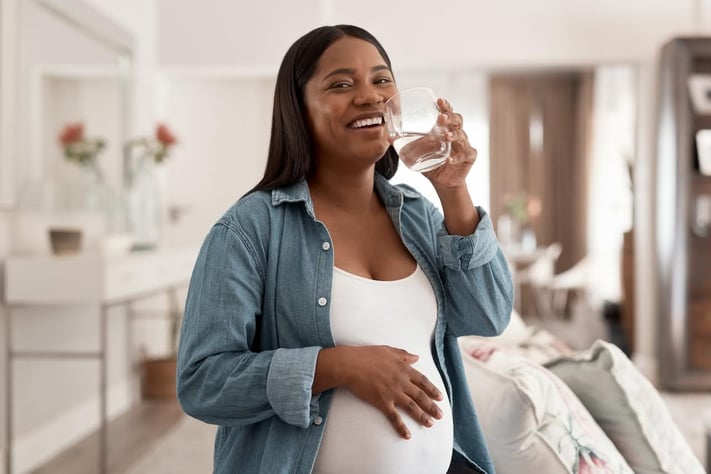 Pregnant woman drinking water to stay hydrated