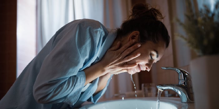 Woman washes her face as part of nighttime skin care routine