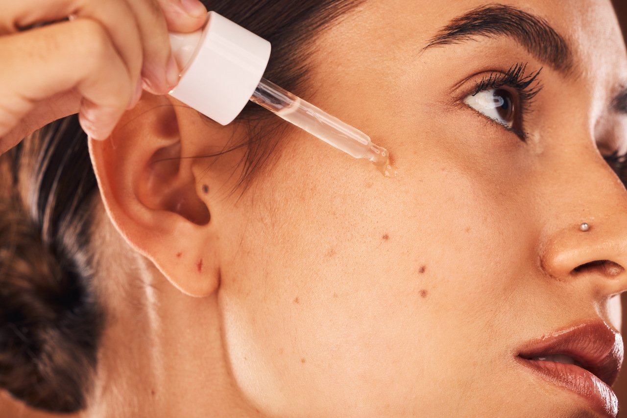 Woman using retinol acne skincare product 