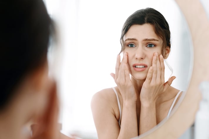 worried girl looking at skin in the mirror