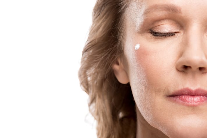 Mature woman applying moisturizer to face