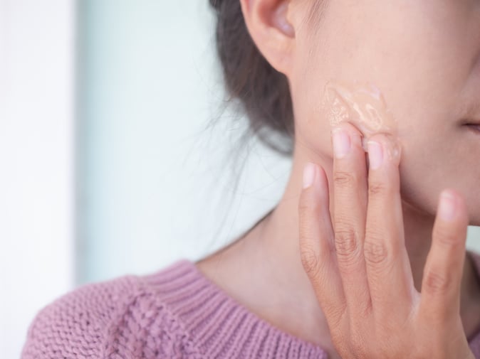 Woman applying skincare product with aloe vera on face