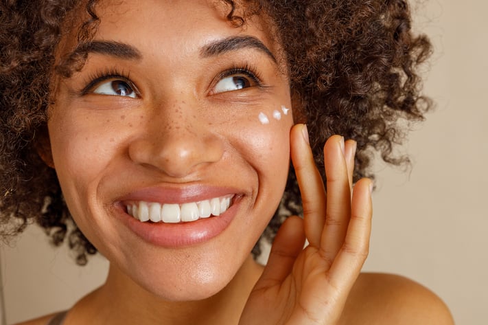 Woman applying moisturizer with spf on face