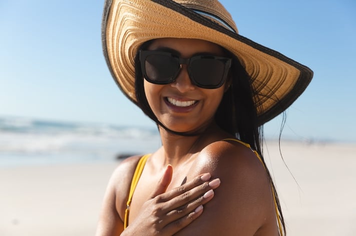 Woman on the beach using sunscreen