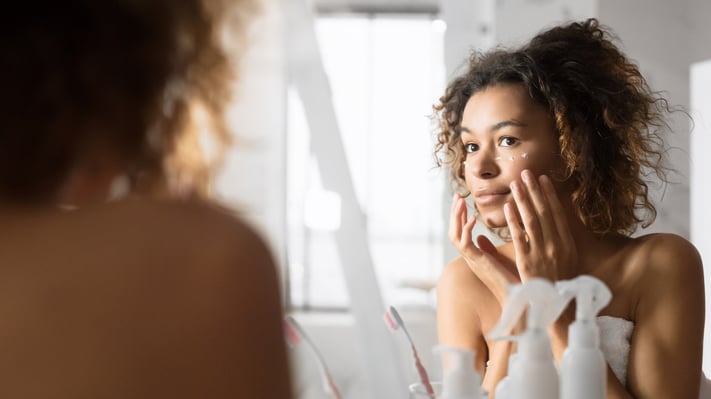 woman looking in the mirror to observe skin improvements