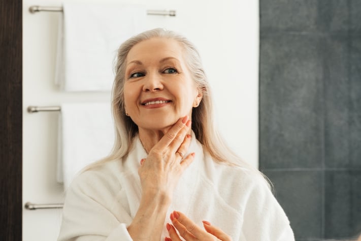 senior woman applying moisturizer to skin