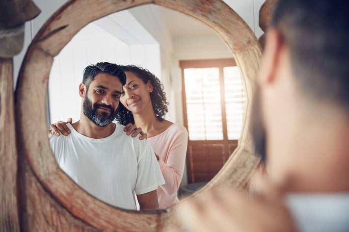 man and woman looking at skin differences in the mirror