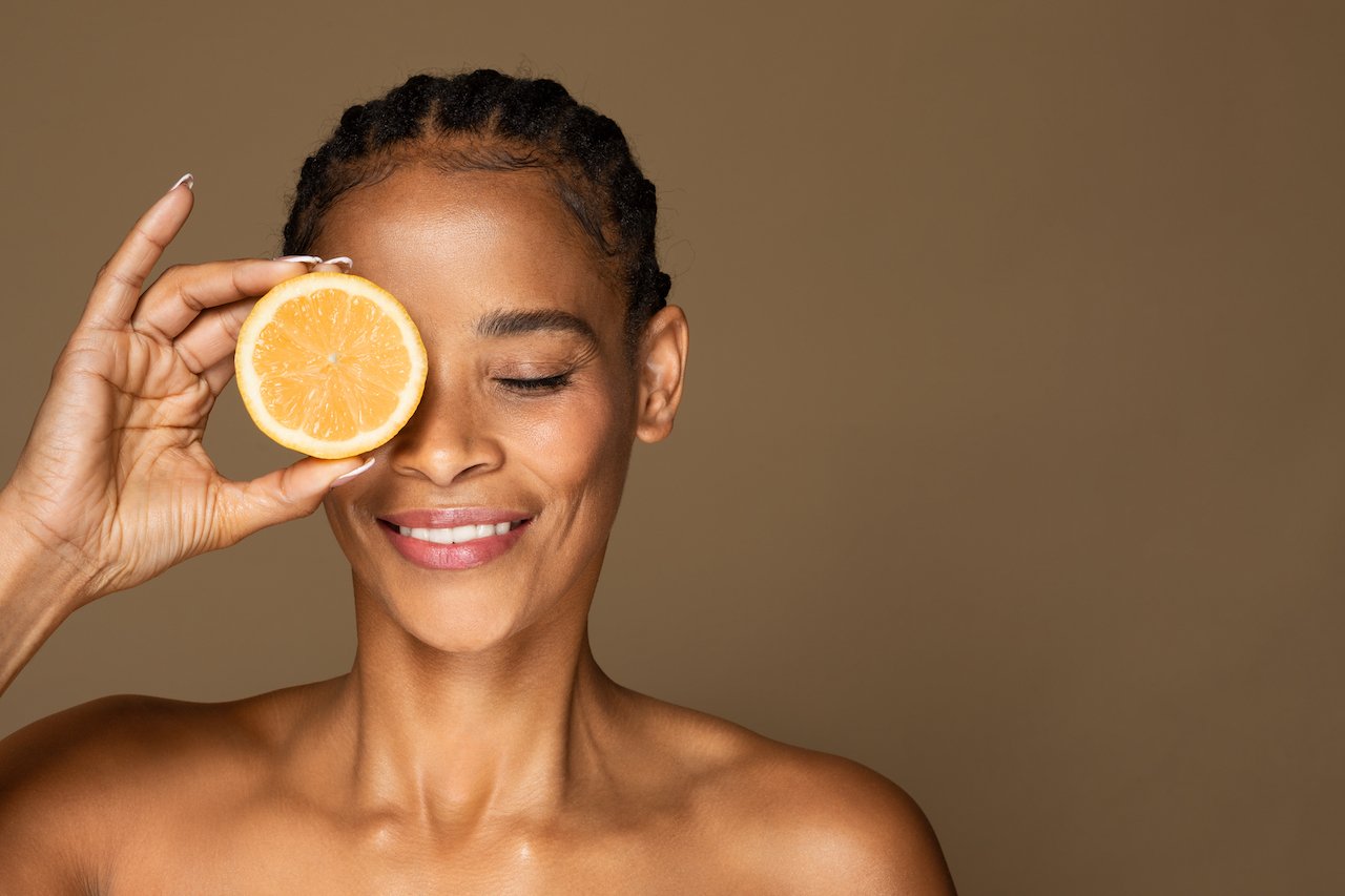 Woman showing orange which is a source of skincare acids