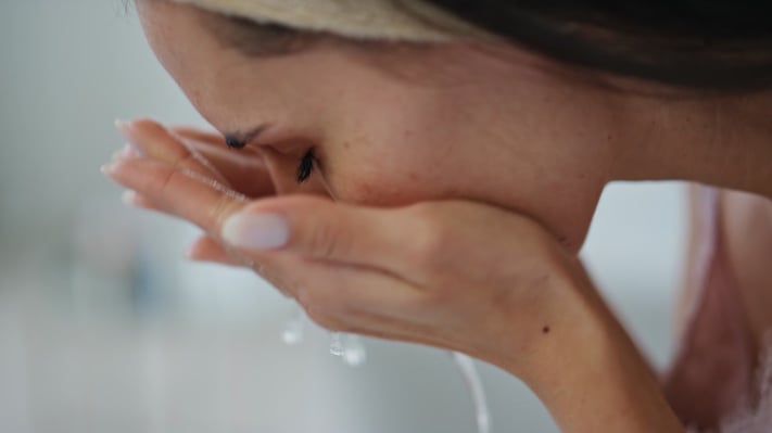 Woman washing her face to assess skin type