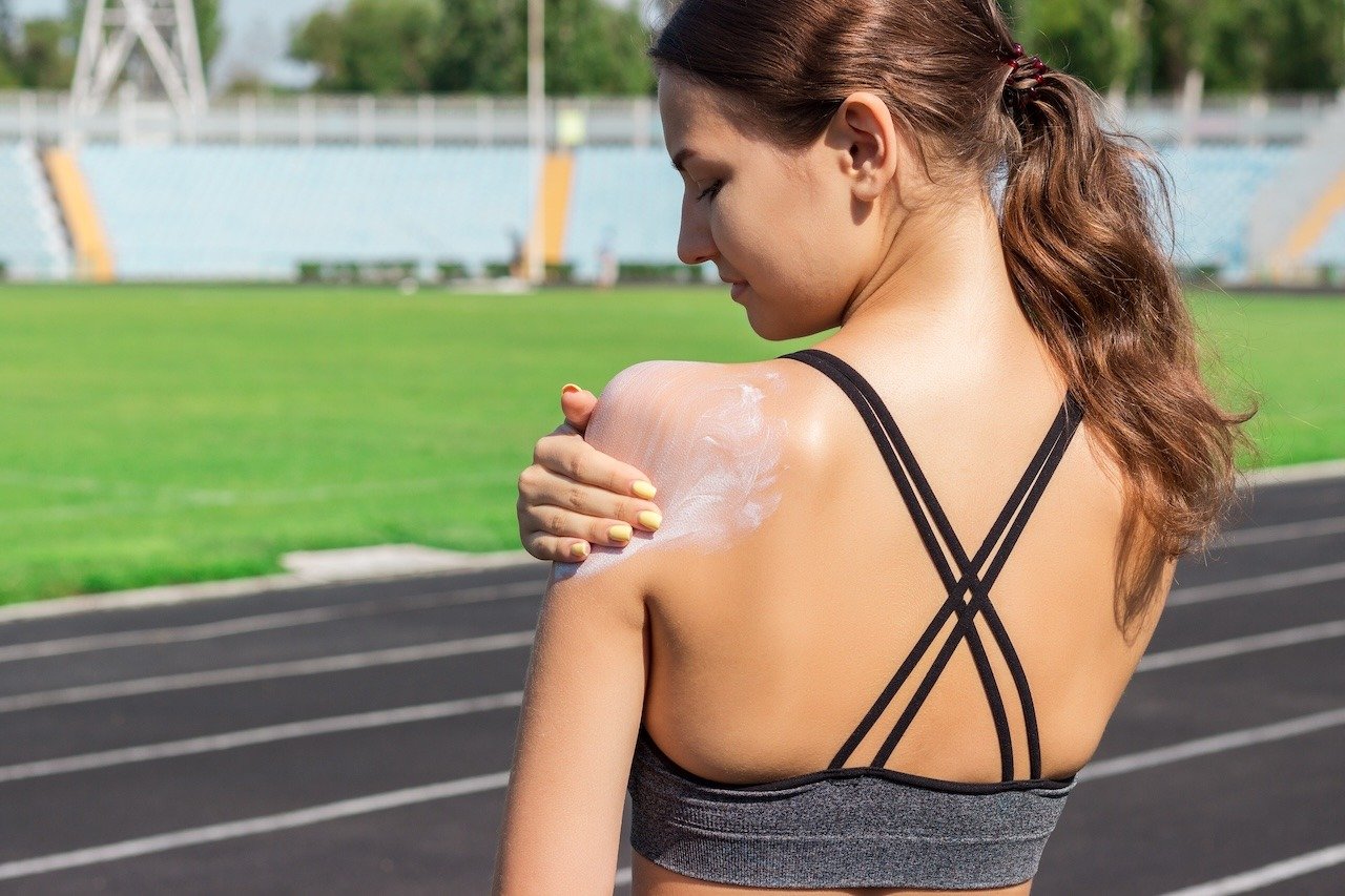 athlete applying sunscreen to protect skin