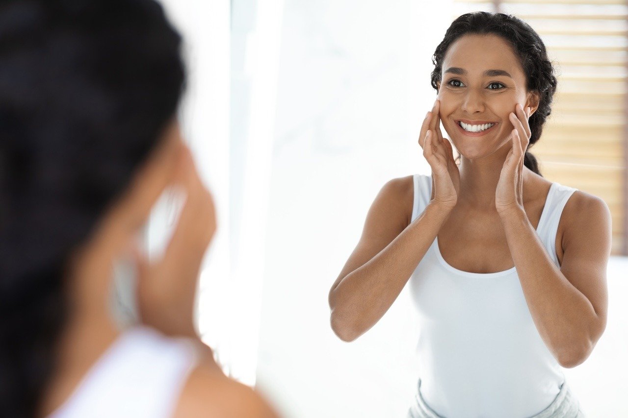 woman looking at skin after holiday skincare routine