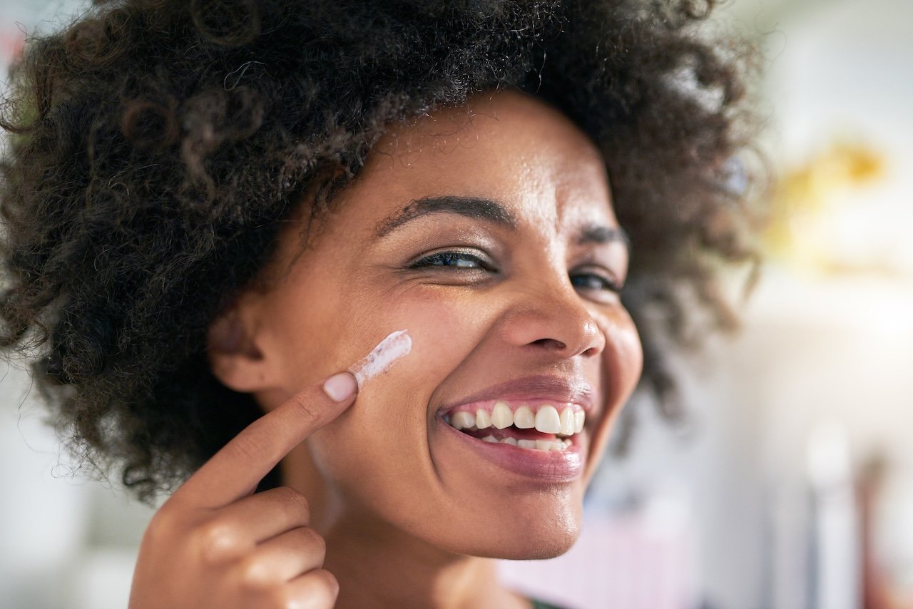 woman applying sunscreen to help prevent dark spots from acne