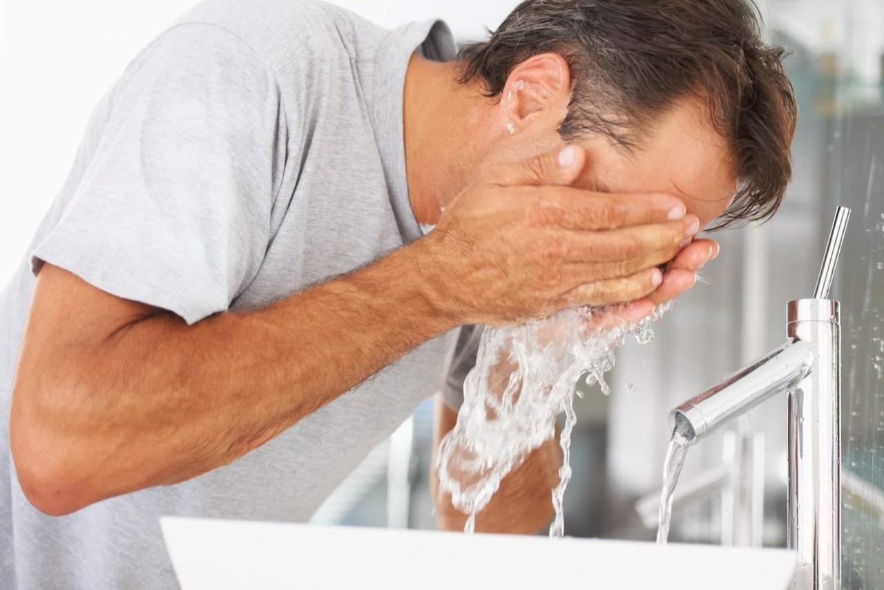 man washing face as part of skincare routine