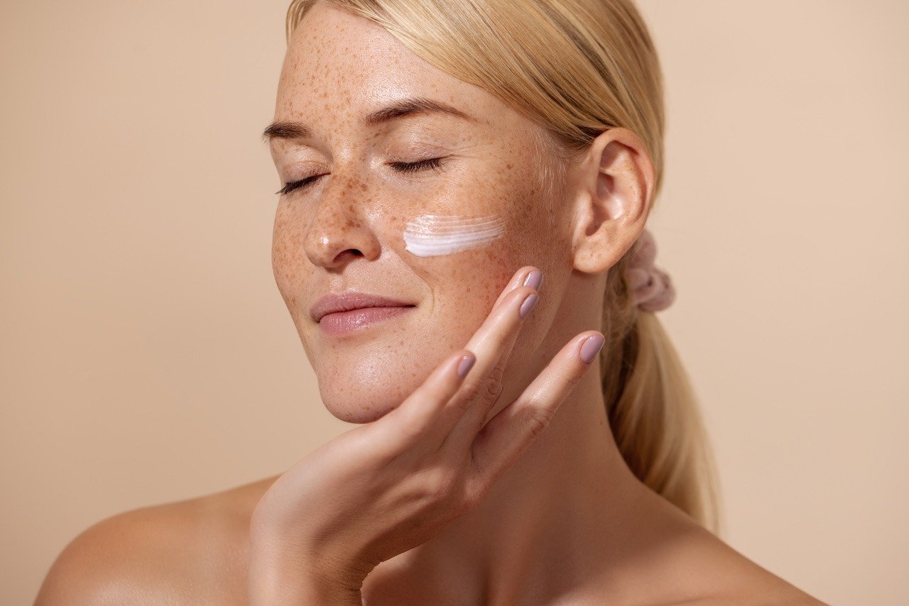 woman applying sunscreen to help prevent skin laxity