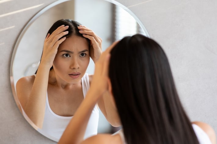woman checking her hair part for hair loss